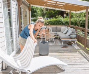 Woman laying towel on lawnchair on deck of home
